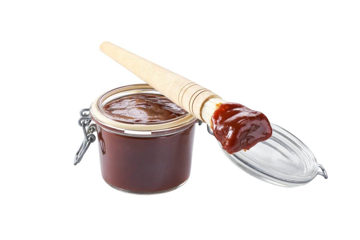 bbq sauce in a jar with barbecue brush isolated on a white background.