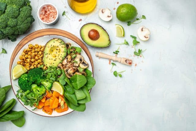 healthy vegan lunch bowl with Avocado, mushrooms, broccoli, spinach, chickpeas, pumpkin on a light background. vegetables salad. Top view.