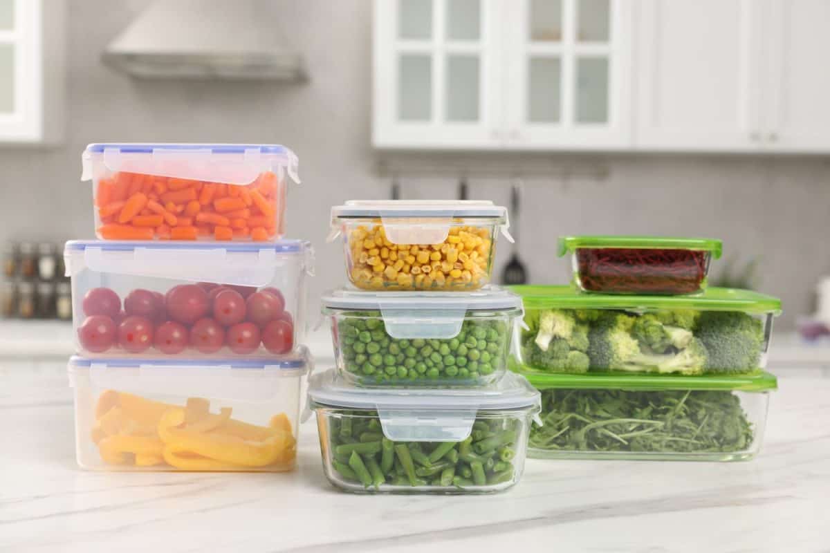 Glass and plastic containers with different fresh products on white marble table in kitchen. Food storage