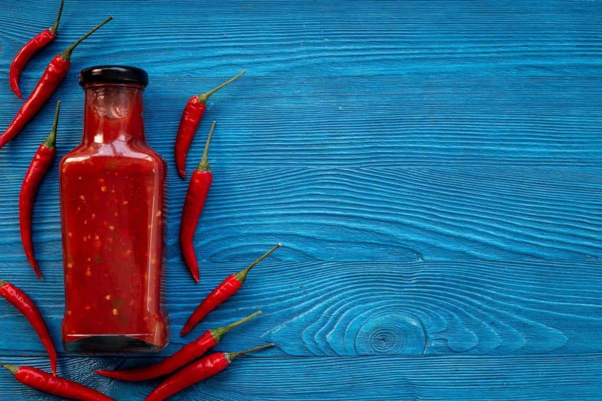 Bottle of spicy sauce tabasco with red hot chili pepper, top view.