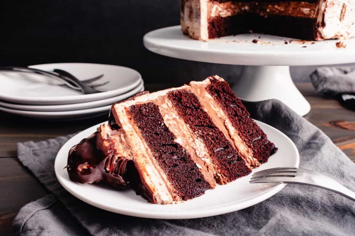 Slice of Hazelnut Chocolate Cake Topped with Chocolate Ganache and Hazelnut Candies: Sliced chocolate layer cake on a dessert plate with a fork