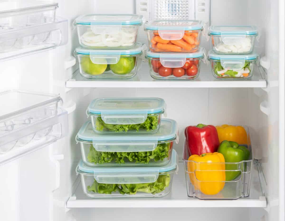 Efficiently Organized Refrigerator Shelves Stocked with Variety of Fresh Produce in Clear Containers, Highlighting Clean Food Storage and Healthy Living in a Modern Kitchen Setting.