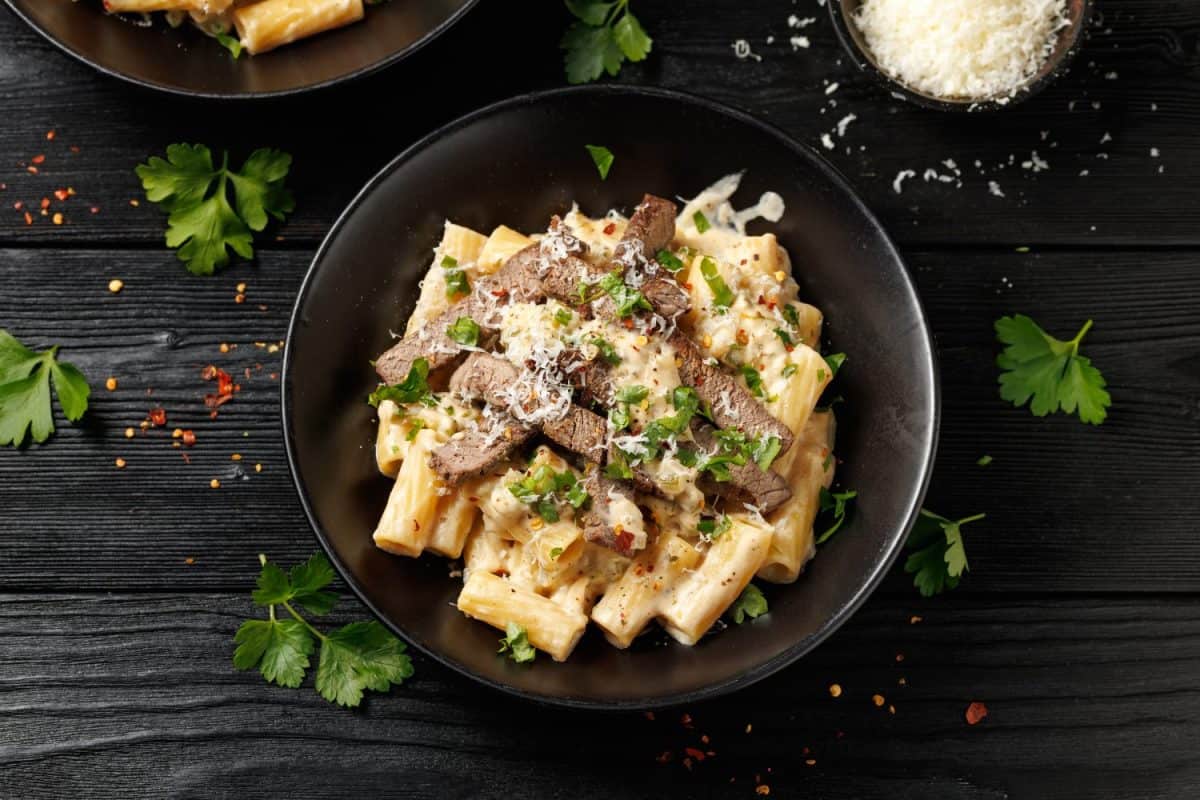 Philly cheese steak pasta in black bowl.