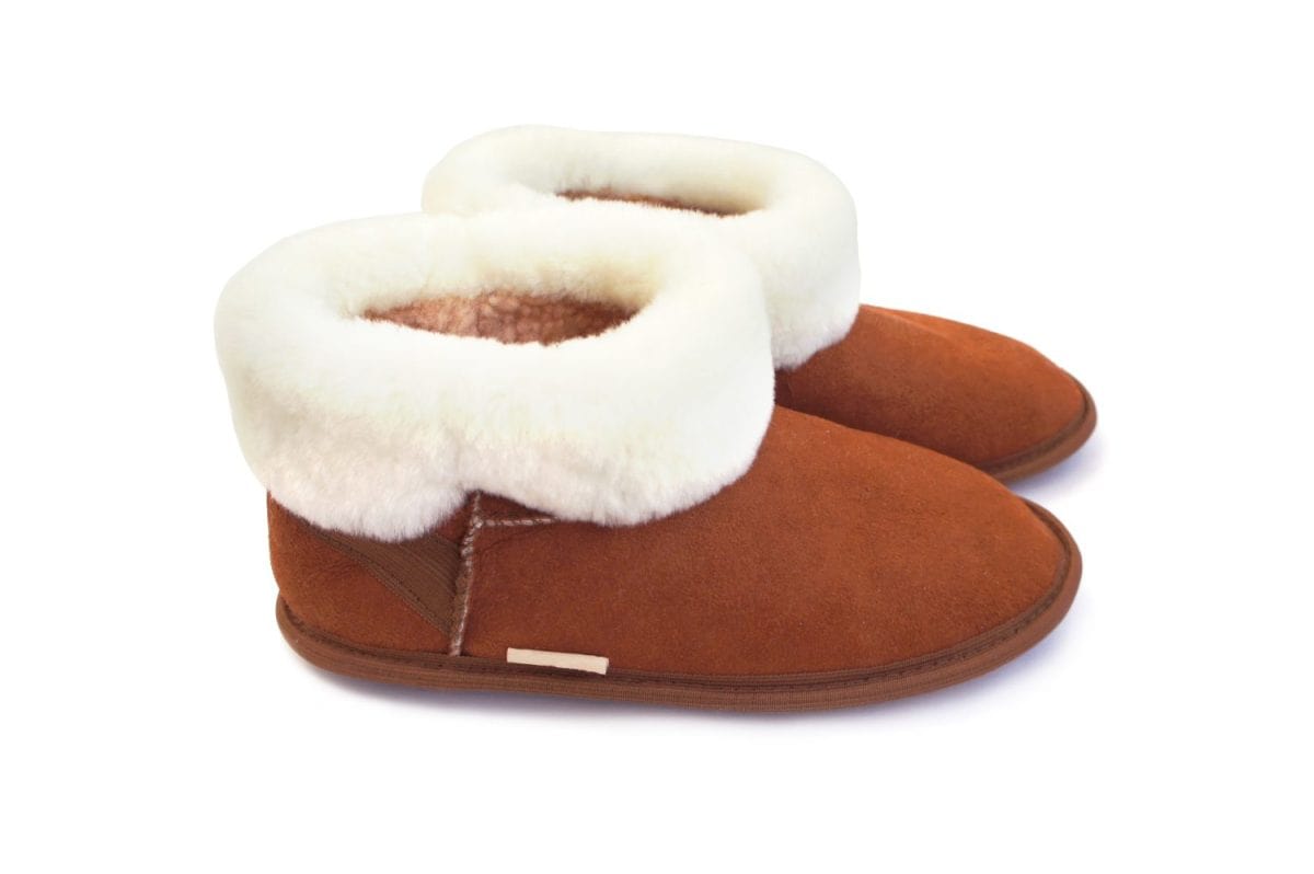 Brown slippers with fur isolated on white background. Home boots with white sheep's wool. Side view.