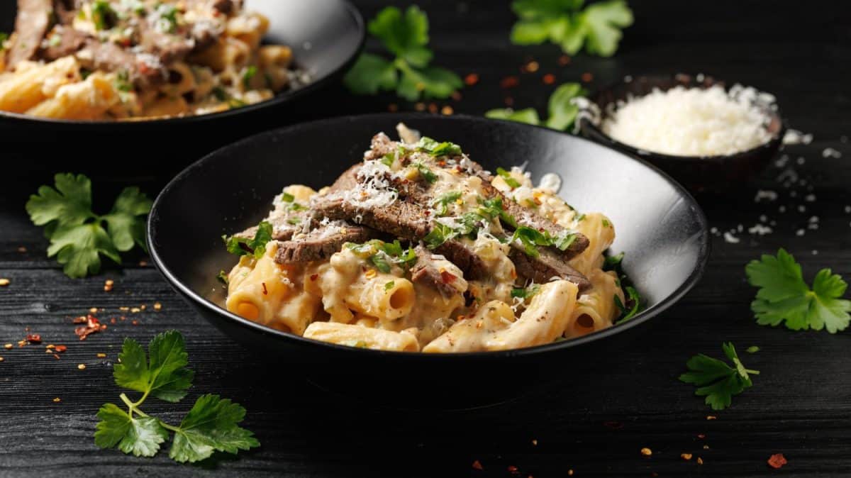 Philly cheese steak pasta in black bowl.