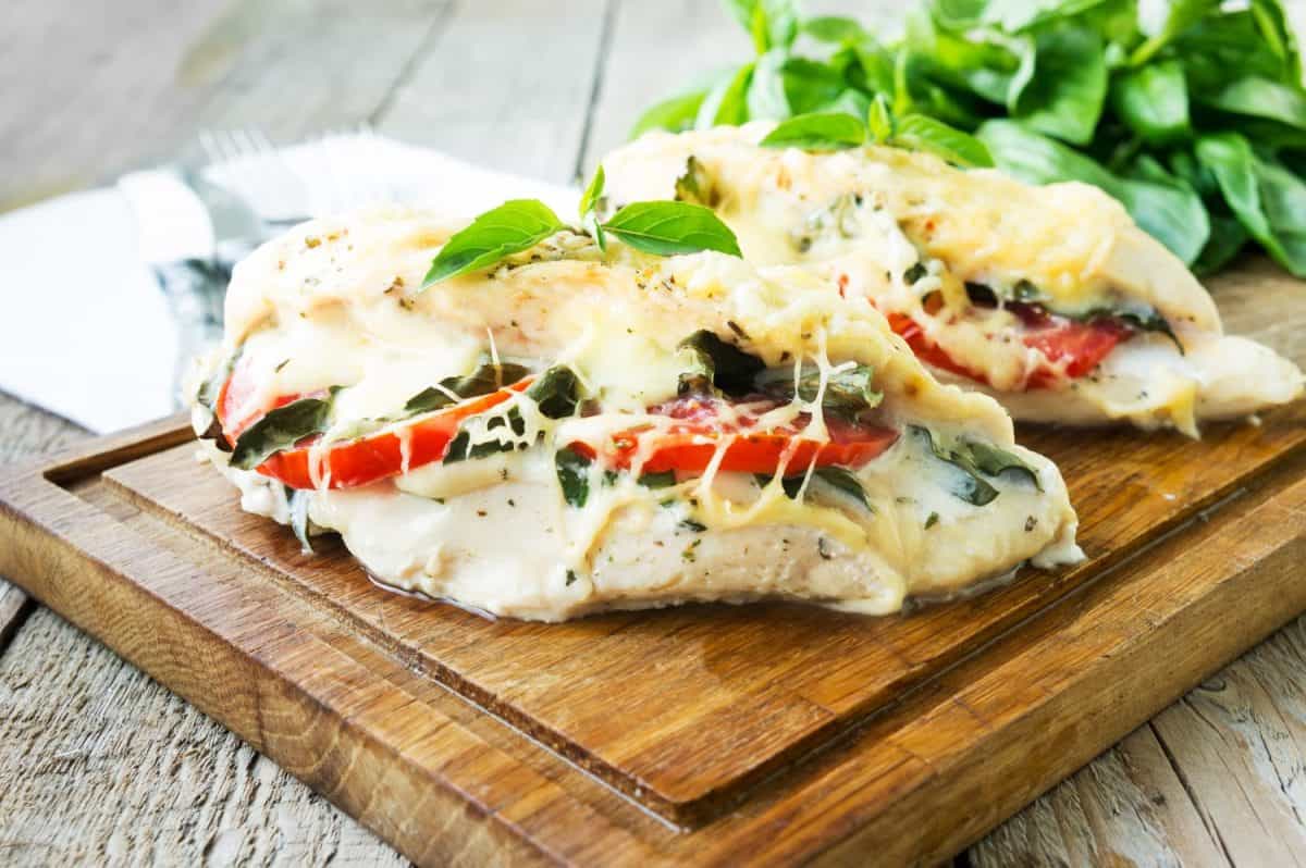 Tomato, mozzarella and basil stuffed chicken breasts on rustic wooden table