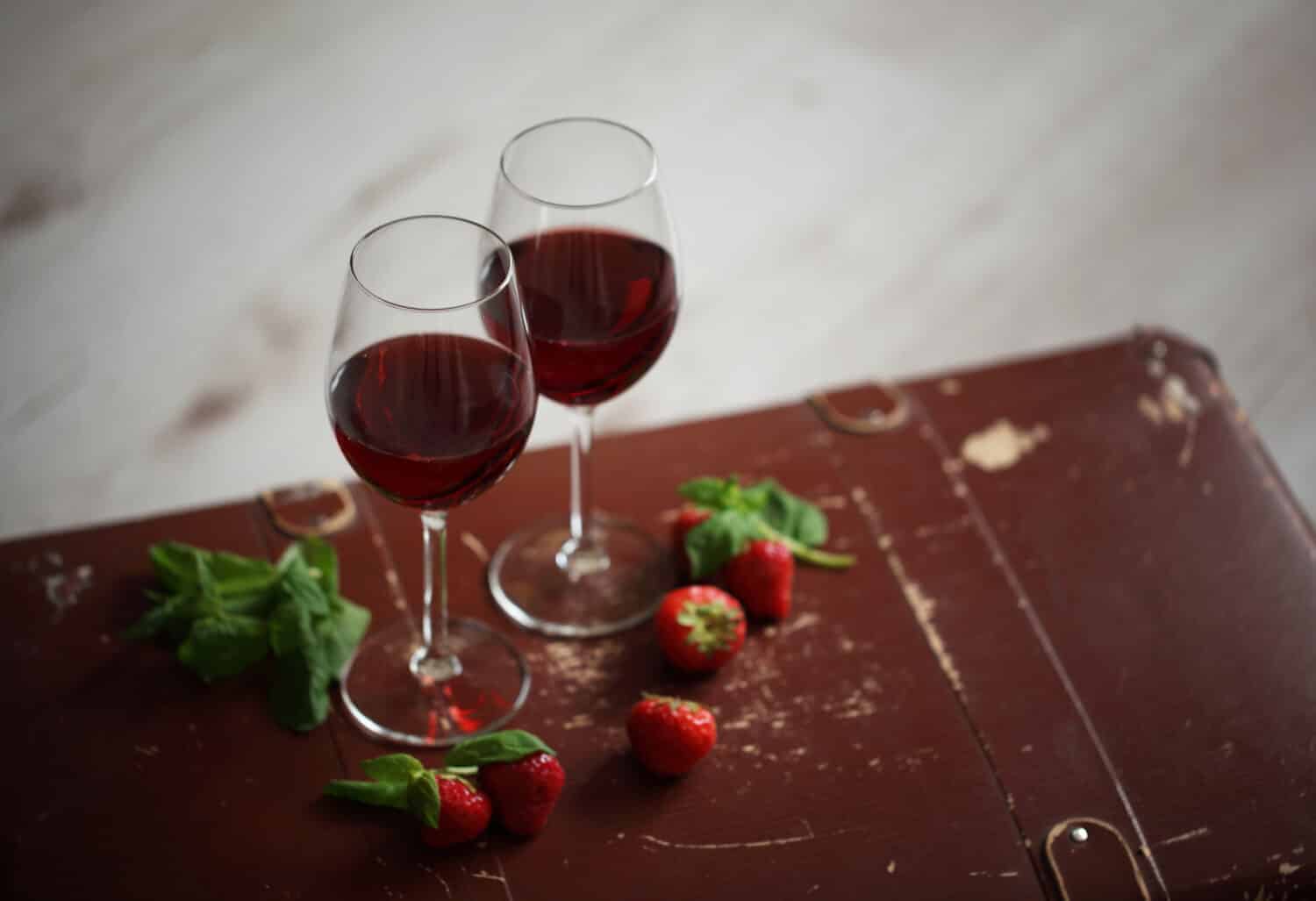 two wineglasses with red wine decorated with strawberry and mint