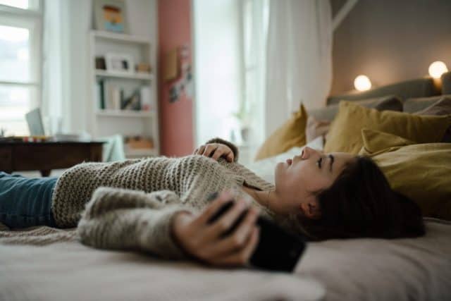 Young teenage girl with smartphone in the room.