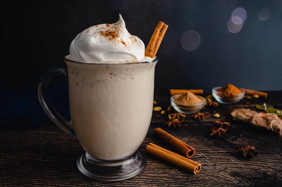 Chai Frappuccino in a Glass Mug Topped with Whipped Cream: Frappuccino made with chai tea and vanilla ice cream garnished with a cinnamon stick