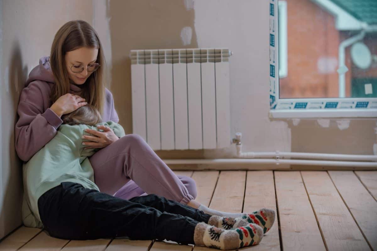 mother sits with her ten-year-old daughter in the attic of the house, the girl is upset, her mother hugged her and calms her down. difficult age and problems at school in children