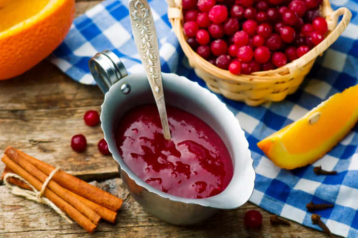 Cranberry Sauce in a serving bowl next to a bowl full of fresh cranberries